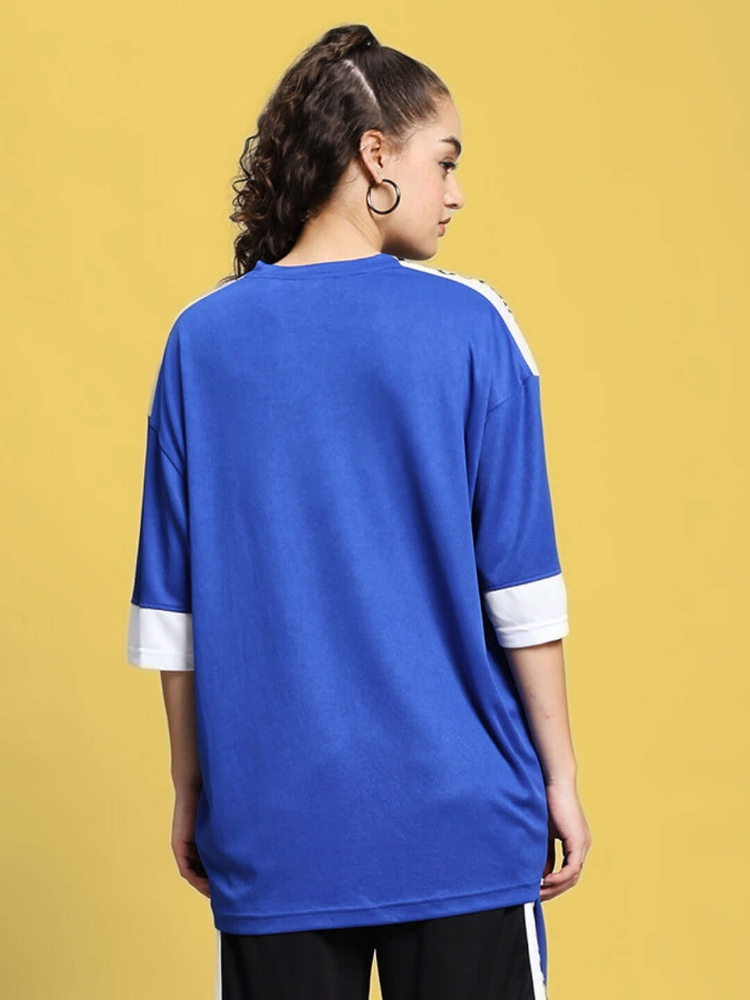 Back view of woman wearing royal blue oversized T-shirt with white sleeves.