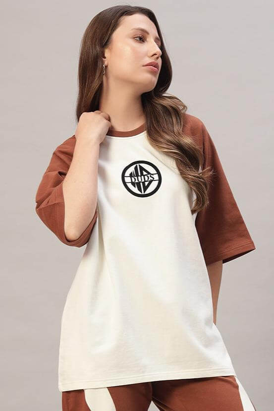 Model wearing women's chestnut raglan oversized T-shirt in off white-brown, featuring a logo on the front, made from premium cotton.