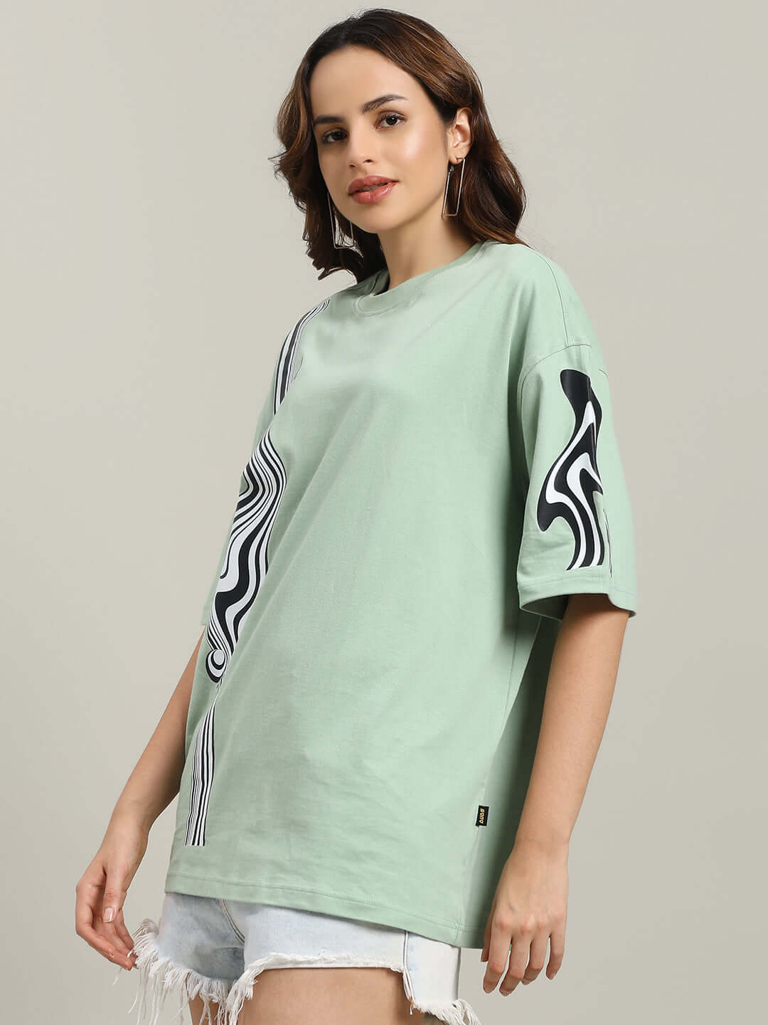 Nyanza green oversized t-shirt for women, featuring a bold design, made from premium cotton French terry, styled with denim shorts.