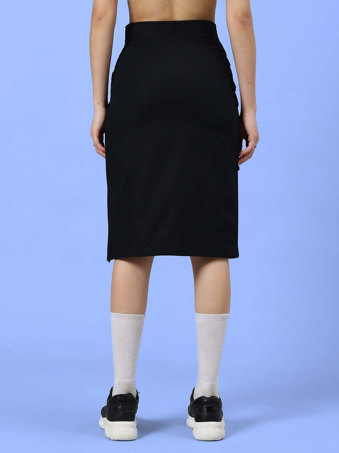 Back view of women's Cooksey designer skirt in black, customizable fit, handmade, shown here paired with white socks and black sneakers.