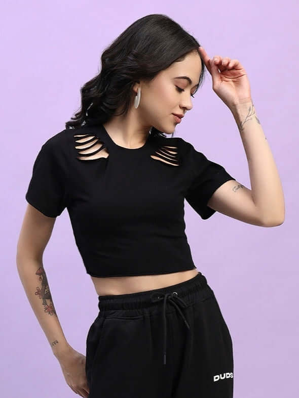 Women's black cozy crop top made of premium heavy gauge fabric with cut-out design, styled with black track pants on light purple background.