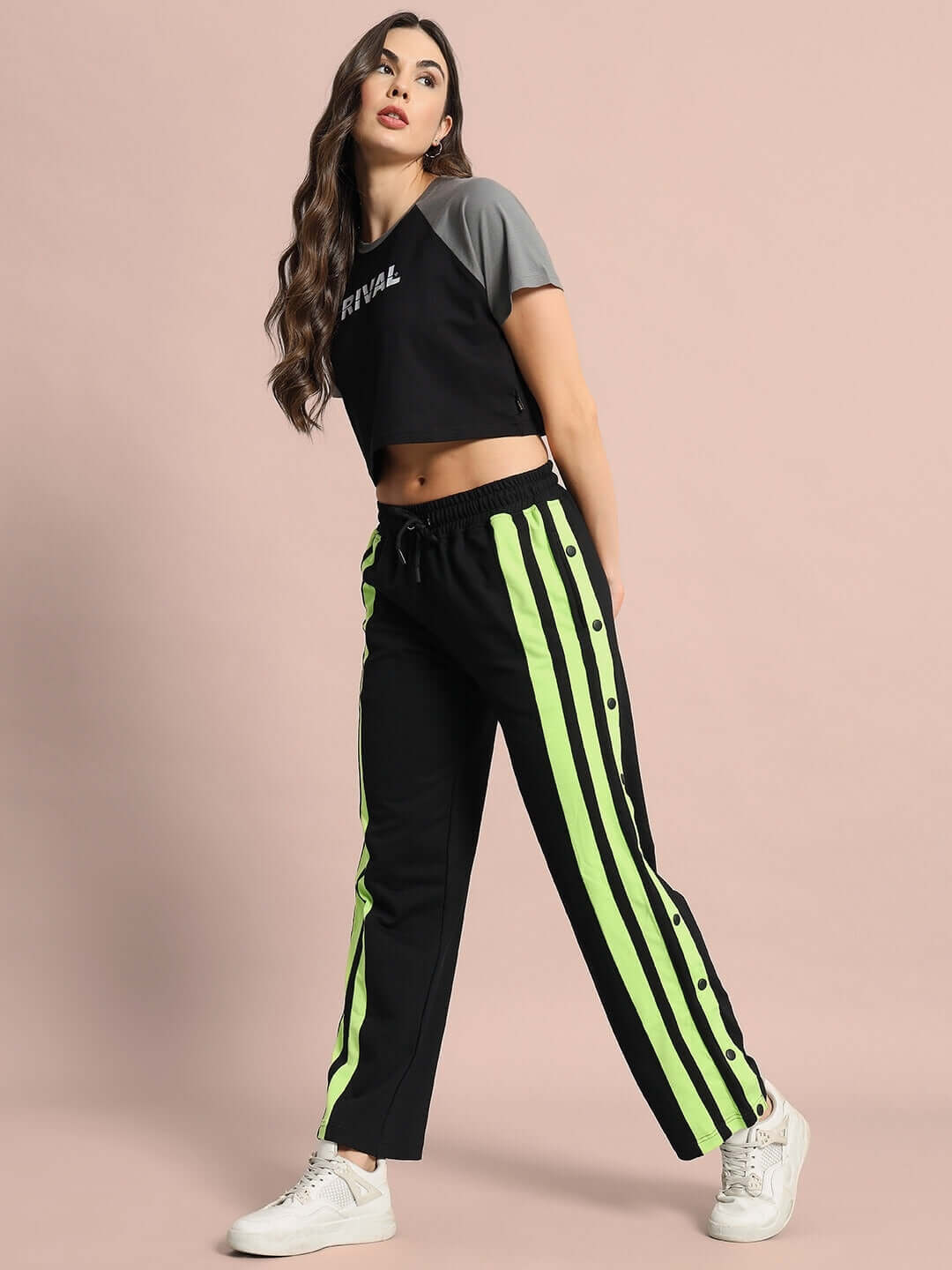 Model wearing Women's Dancer Joggers in black with neon green stripes, styled with a crop top and white sneakers.