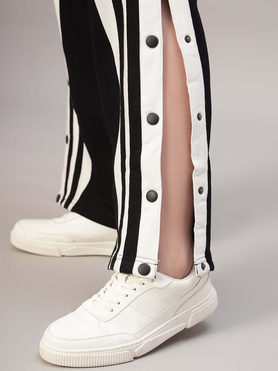 Close-up of Women's Dancer Joggers in Black-White with snap buttons, paired with white sneakers, showcasing modern athleisure style.