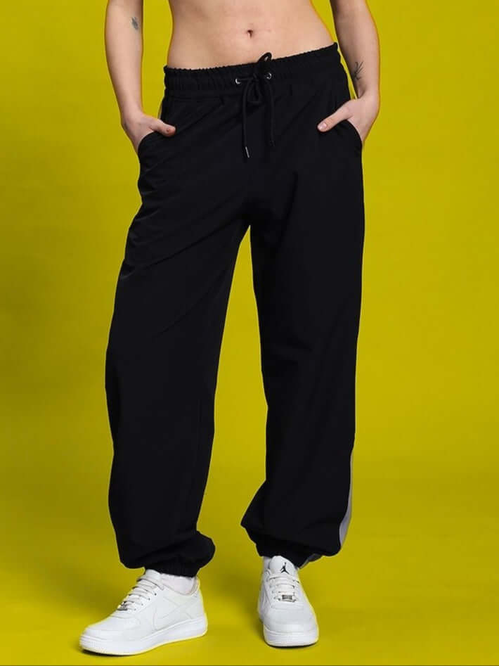 WOMEN'S DANNY RELAXED FIT CARGO PANTS BLACK showcased against a yellow background with street-style aesthetic.