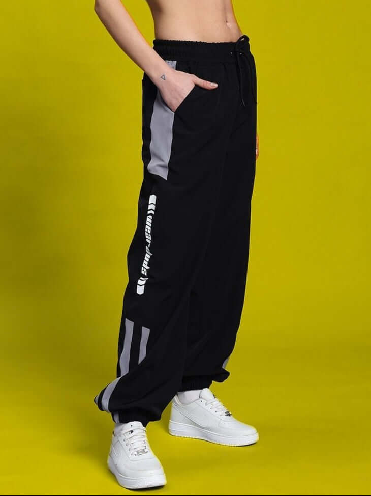 Person wearing WOMEN'S DANNY RELAXED FIT CARGO PANTS BLACK against yellow background.