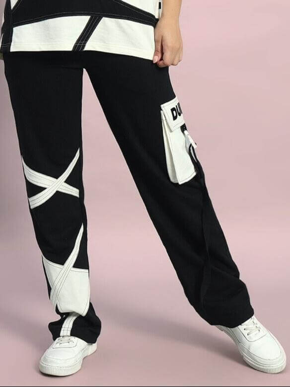 Woman wearing black jogger pants with white accents and pockets, paired with white sneakers.
