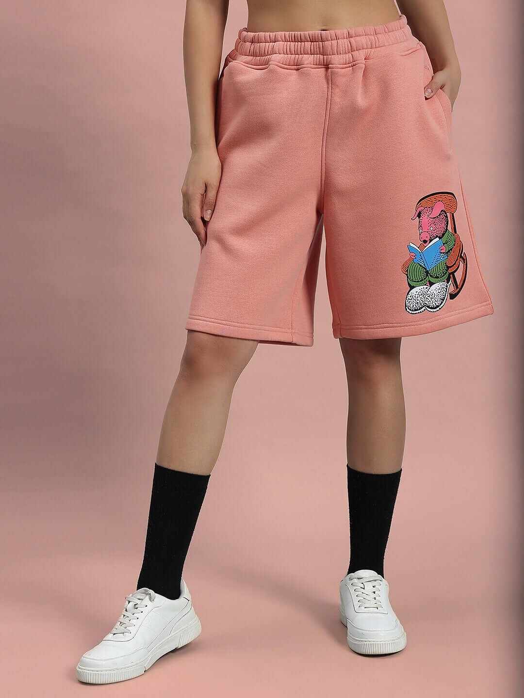 Model wearing WOMEN DELIBERATE FLEECE SHORTS PEACH showcasing comfort and style with vibrant graphic design.