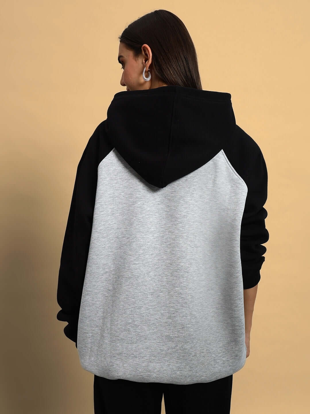 Back view of a WOMEN DELUXE FLECCE OVERSIZE HOODIE BLACK MELANGE GREY with a roomy hood and trendy oversized fit.