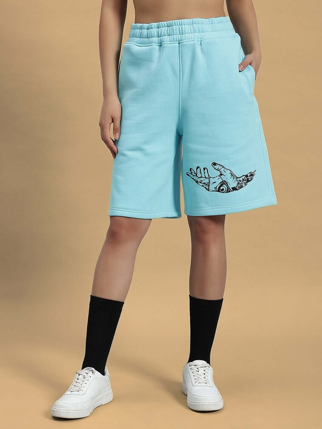 Woman wearing WOMEN DEMON FLEECE SHORTS SKY BLUE with hand graphic, black socks, and white sneakers.