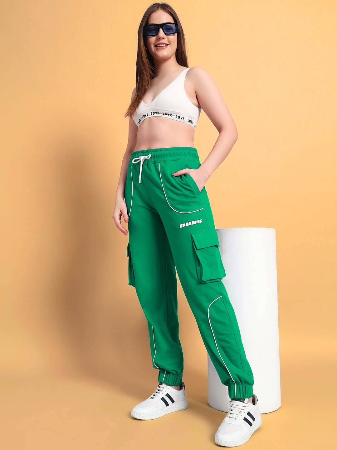 Woman wearing green relaxed-fit joggers with pockets, styled with white sneakers, showcasing casual streetwear look.