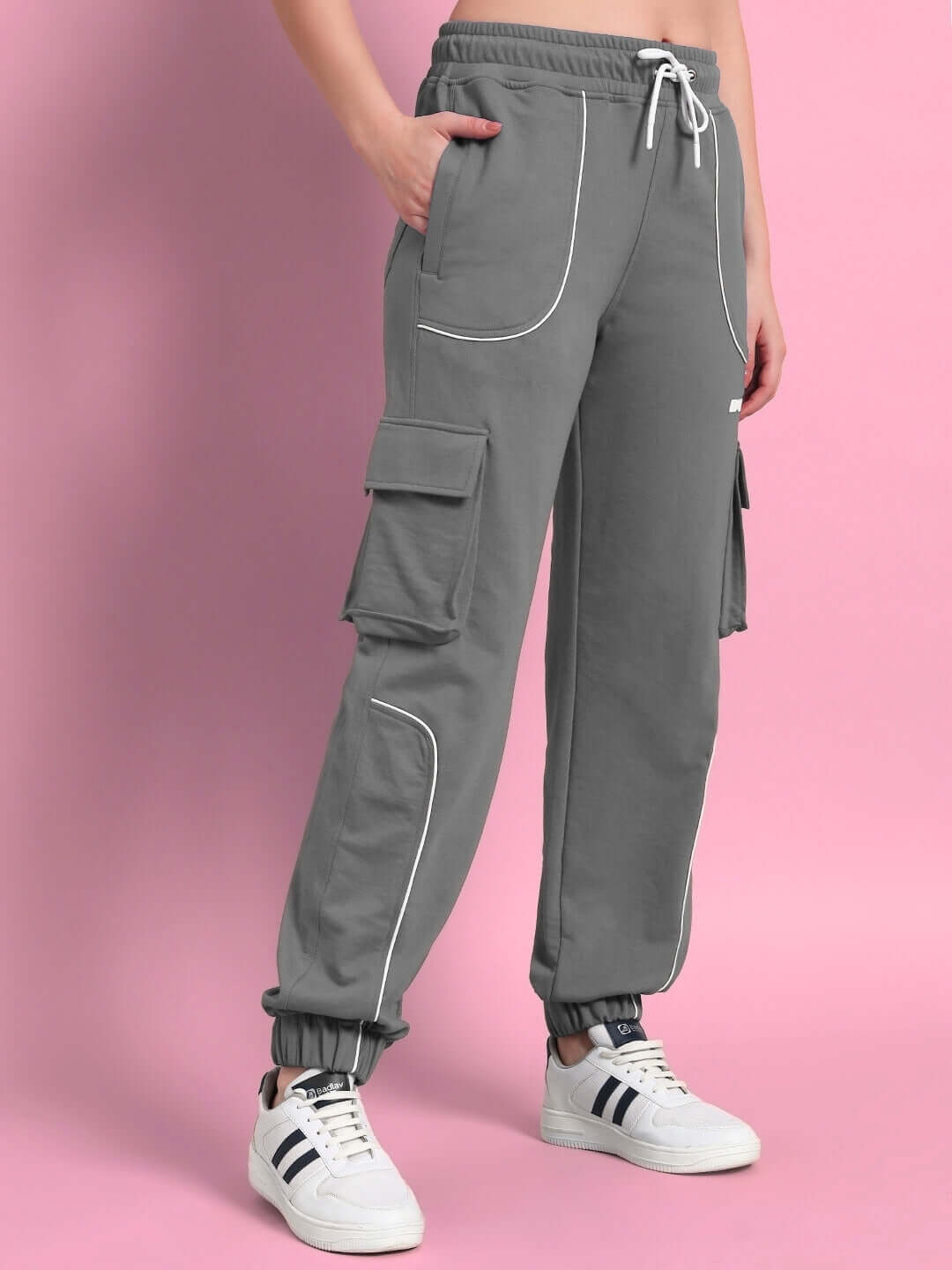 Women's grey relaxed-fit joggers with cargo pockets and white shoes, showcasing stylish and comfortable casual wear.