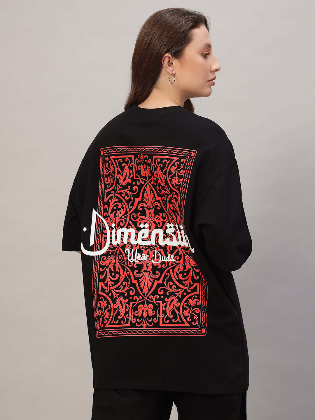 Model wearing women's black oversized t-shirt with red intricate back design, made of premium cotton French terry, by Color By Colours.