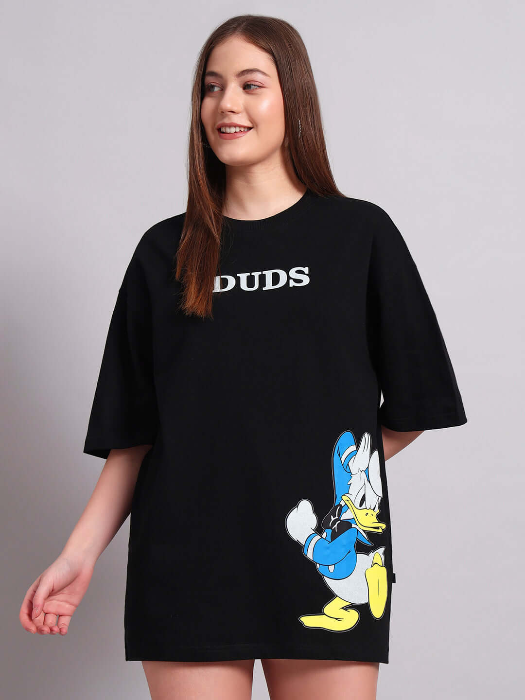 Woman wearing black oversized T-shirt with Donald Duck print, made from premium cotton blend. Stylish and comfortable fashion.