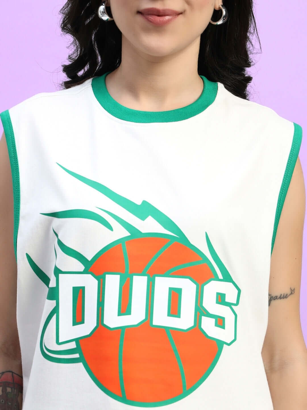 Woman wearing sleeveless top with basketball graphic and lettering, purple background, fashion shot.