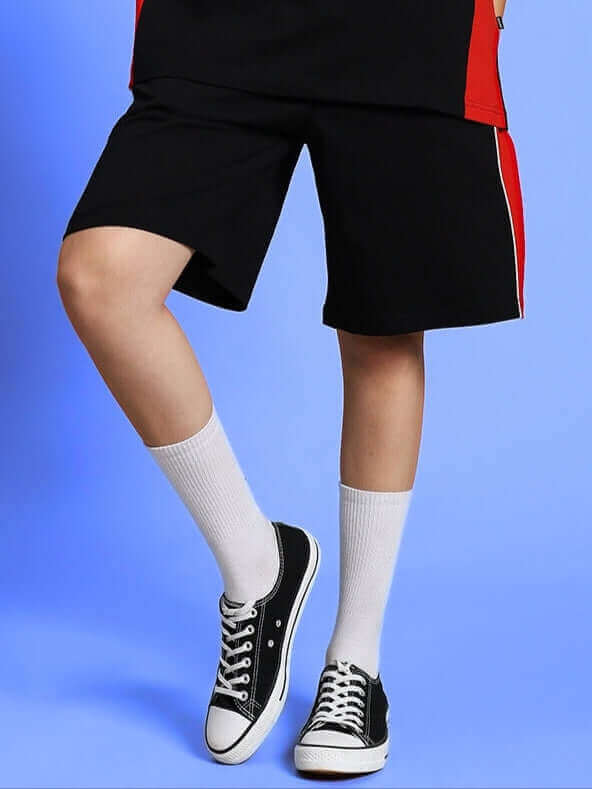 Women's Drift Regular Fit Black Shorts, customizable for custom fit, shown with red accents and classic sneakers on a blue backdrop.