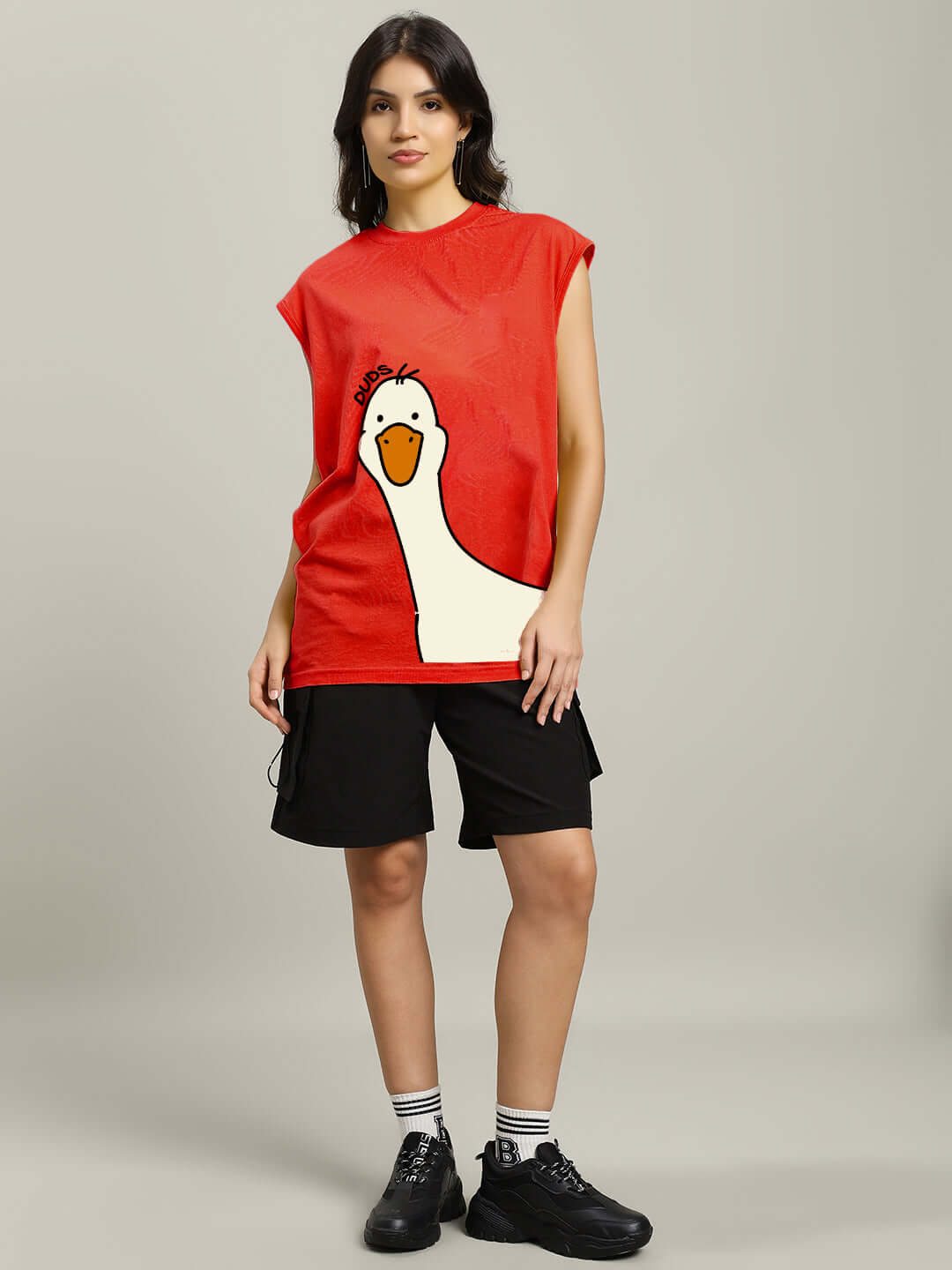 Woman wearing a red gym T-shirt with a duck illustration, paired with black shorts and shoes, showcasing casual fitness apparel.
