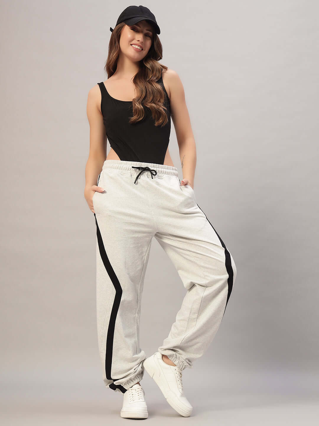 Woman wearing Women's DUDS Frame Joggers in melange grey with black stripes, paired with a black tank top and cap.