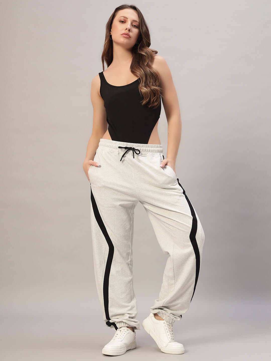 Woman wearing melange grey Duds frame joggers paired with a black tank top, showcasing stylish comfort and modern design.