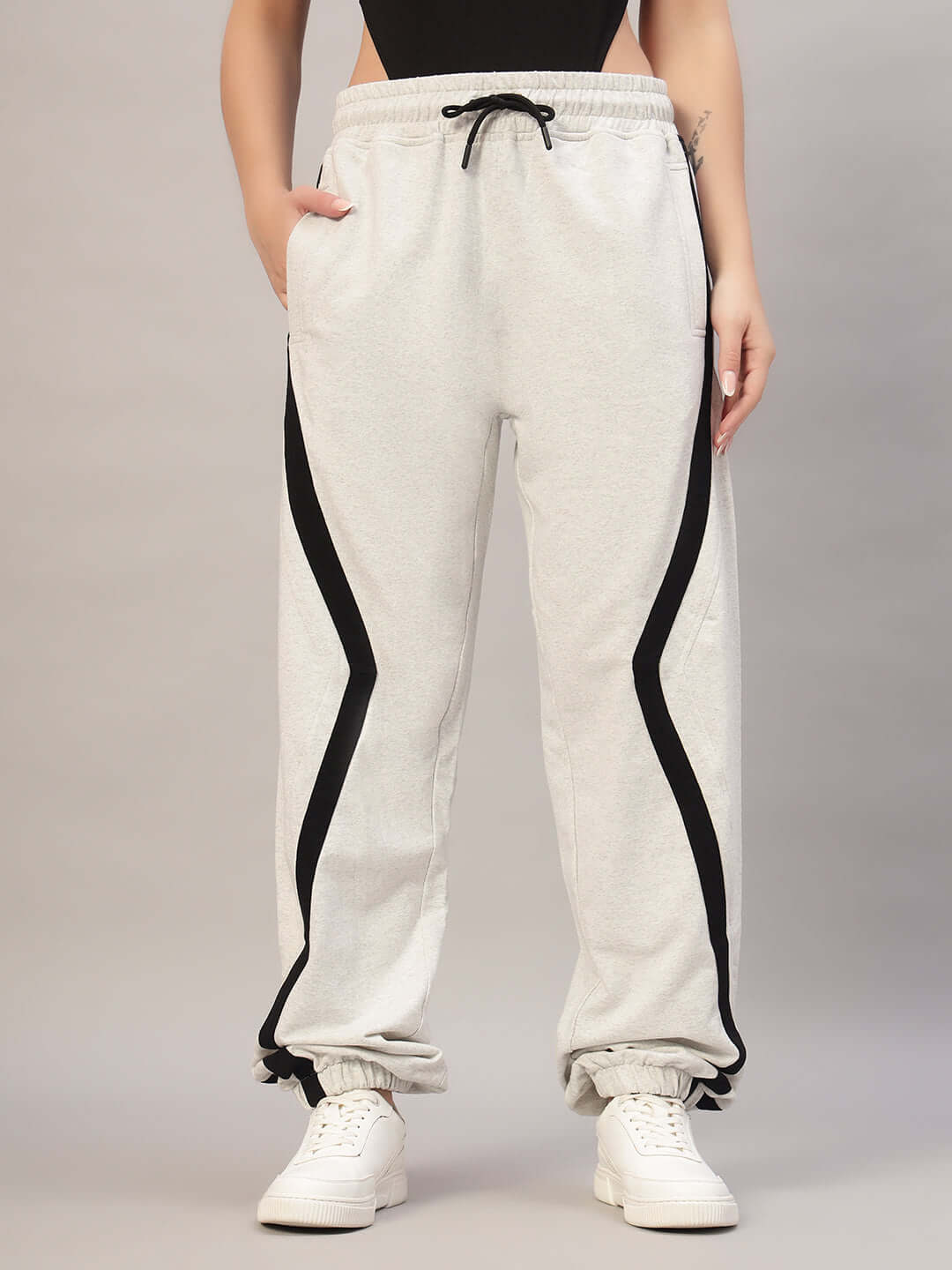 Woman wearing melange grey joggers with black stripes, featuring adjustable waist and cuffed ankles. Ideal for custom sizing options.
