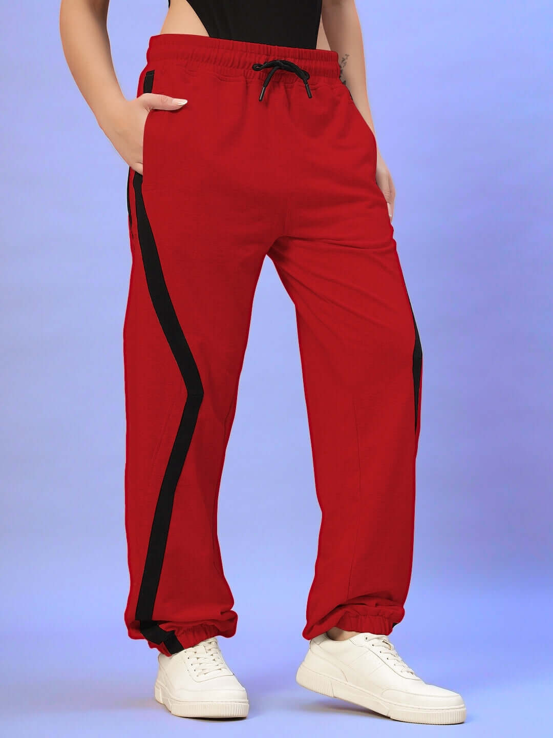 Red women's joggers with black stripe and adjustable drawstring, made by DUDS, showcased in a blue background.