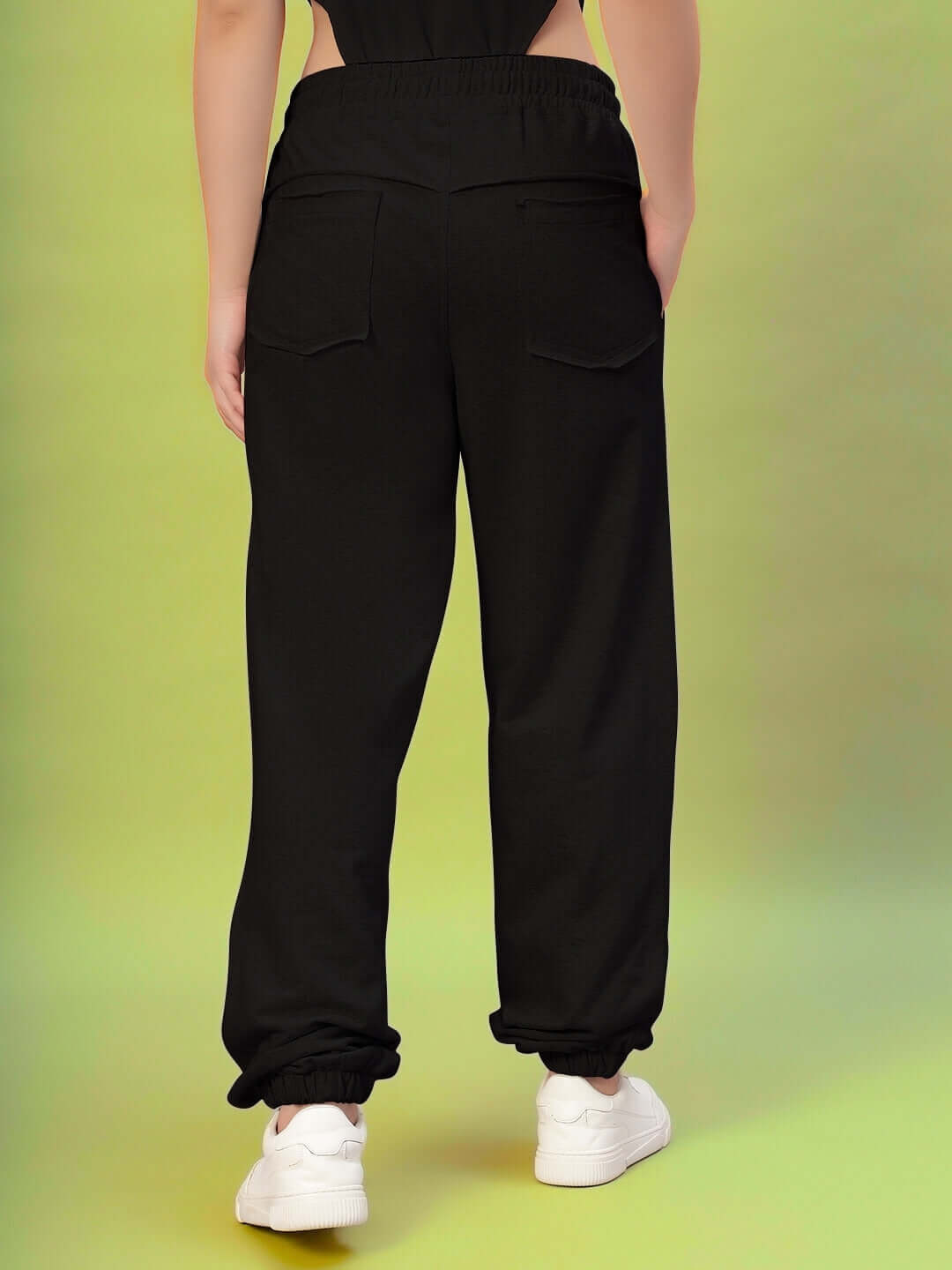 Back view of Women's DUDS Graze Joggers in black, featuring a relaxed fit and elastic waistband, paired with white sneakers.