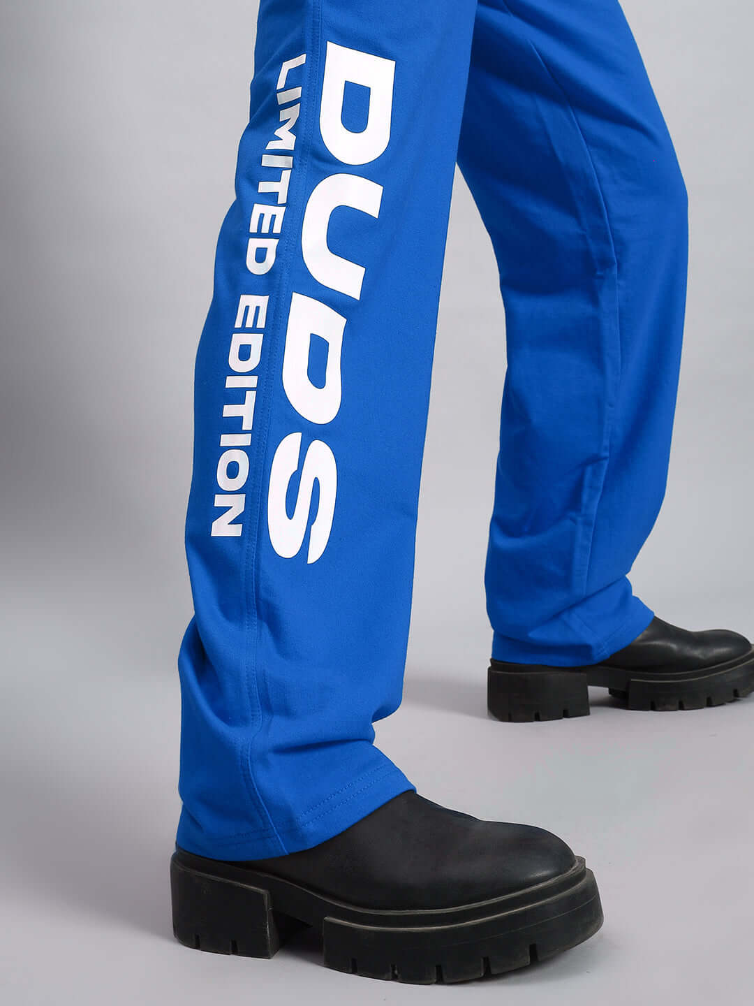Close-up of blue Women's DUDS Limited Edition Jogger showcasing 'DUDS Limited Edition' text on the leg, paired with black boots.