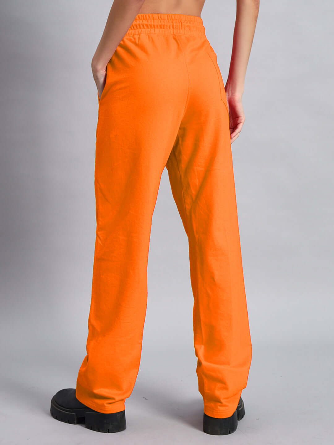 Back view of WOMEN'S DUDS LIMITED EDITION JOGGER ORANGE with elastic waistband, showcased by a model wearing black shoes.