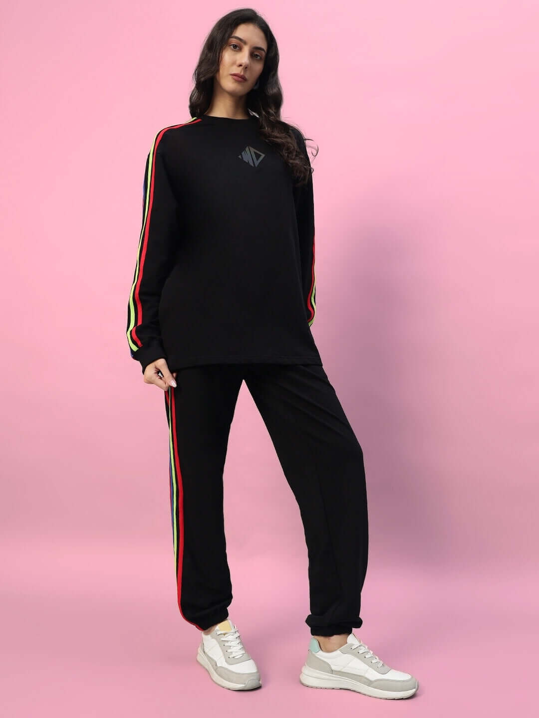 Woman wearing black joggers with rainbow stripes, showcasing WOMEN'S DUDS RAINBOW COLORFUL STRIPE JOGGERS against a pink background.