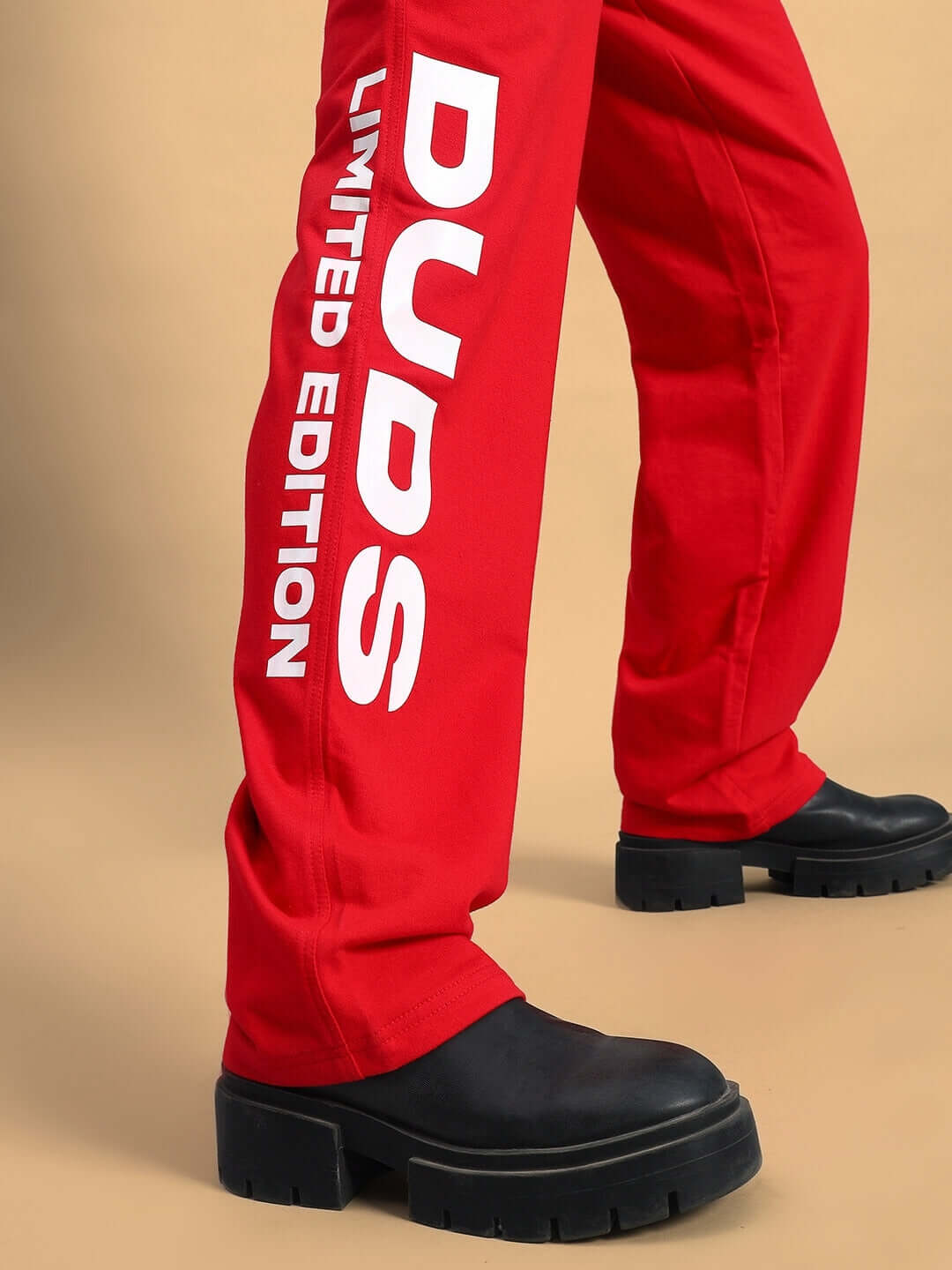 Close-up of Women's DUDS Limited Edition Jogger in red, featuring bold lettering on leg and black boots.