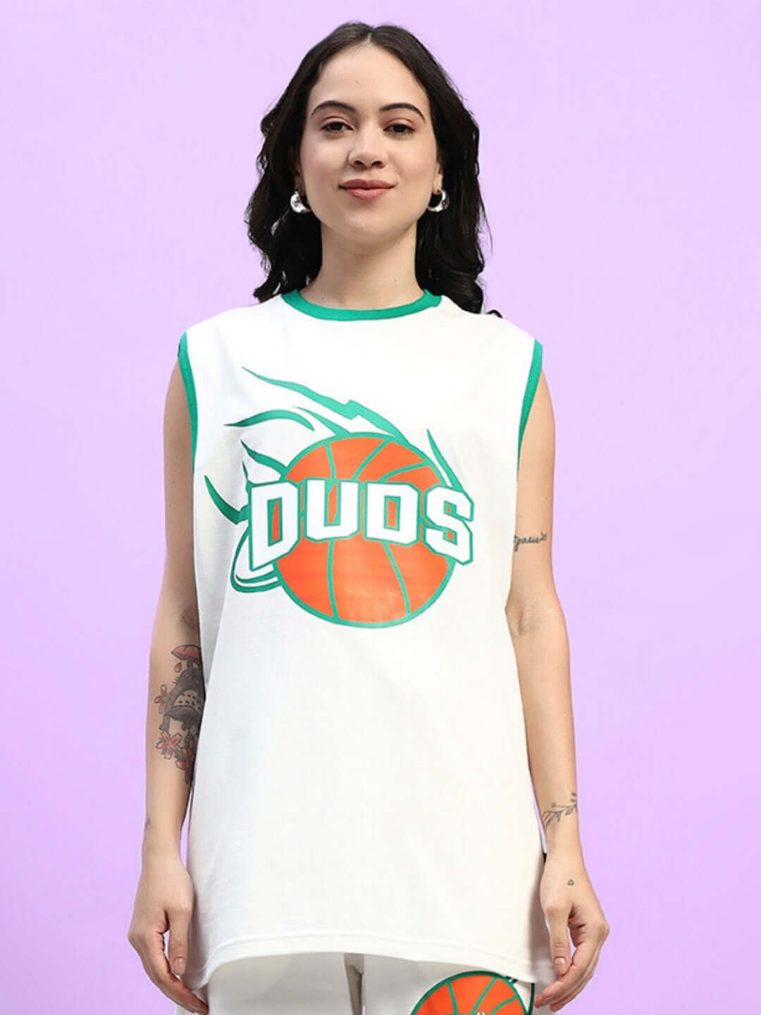 Woman wearing oversized off-white t-shirt with 'DUOS' basketball logo, standing against a purple background.