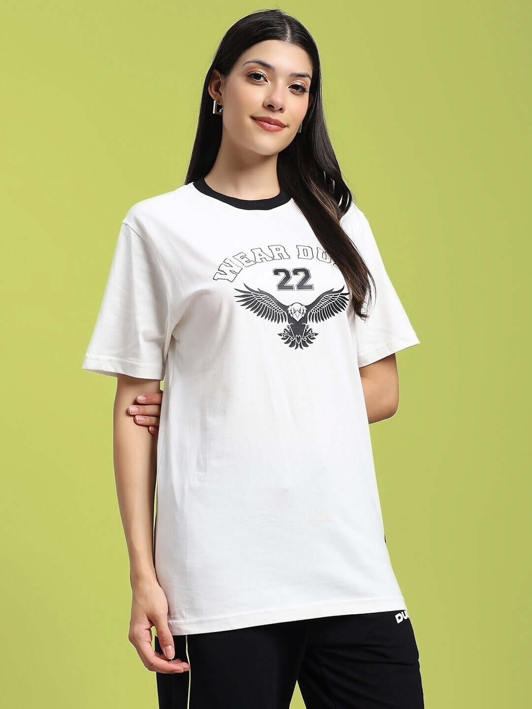 Woman wearing a white Women's Eagle Wings Regular Fit T-shirt made from 100% cotton, featuring eagle print, against a green background.