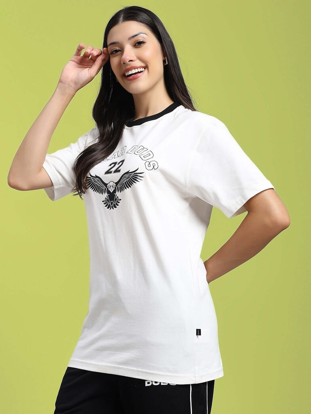 Woman wearing white Women's Eagle Wings T-shirt, regular fit, 100% cotton, with eagle print design and black accents, on light green background.