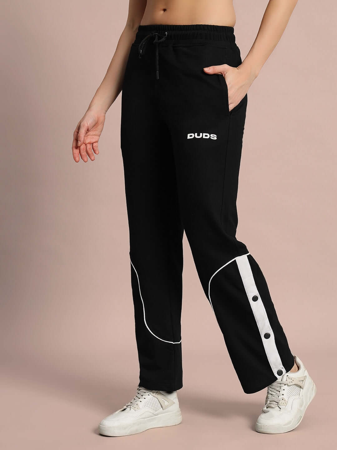 Model wearing black DUDS women's Eddie contrast joggers with white side stripe detail, showcasing casual athletic wear.