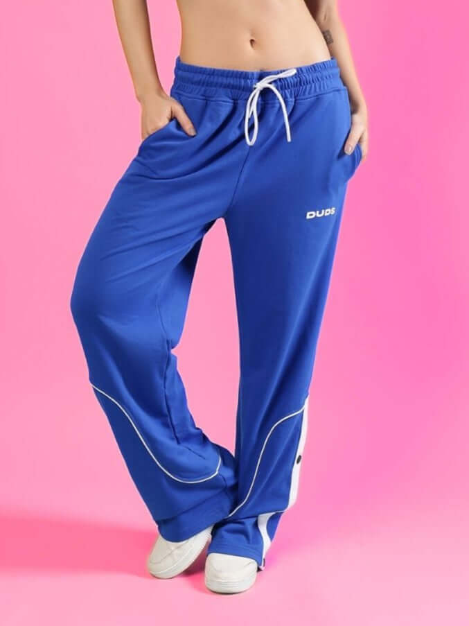 Woman wearing blue women's Eddie contrast joggers from DUDS, featuring customizable fit options, on a pink background.