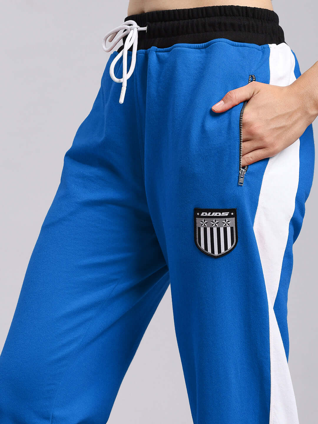 Women's elegant blue joggers with relaxed fit, featuring side pockets and a stylish badge. Made by DUDS, available for custom fit orders.