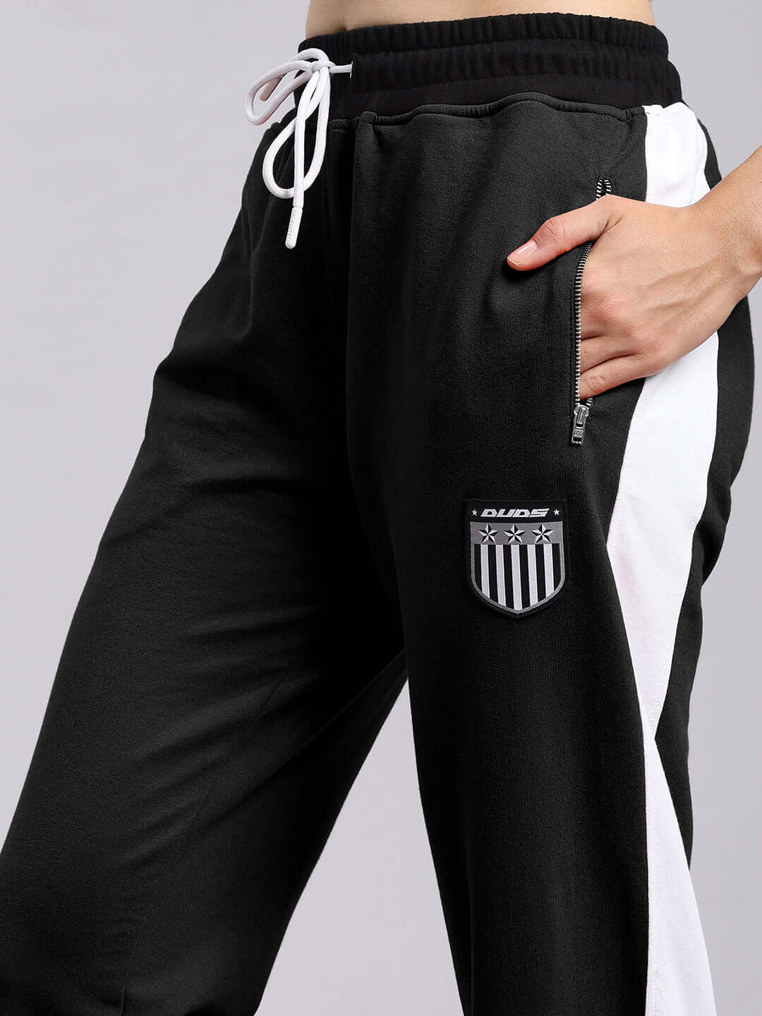Women's black elegant relaxed-fit joggers by DUDS with side pocket and logo, featuring white stripe detail.