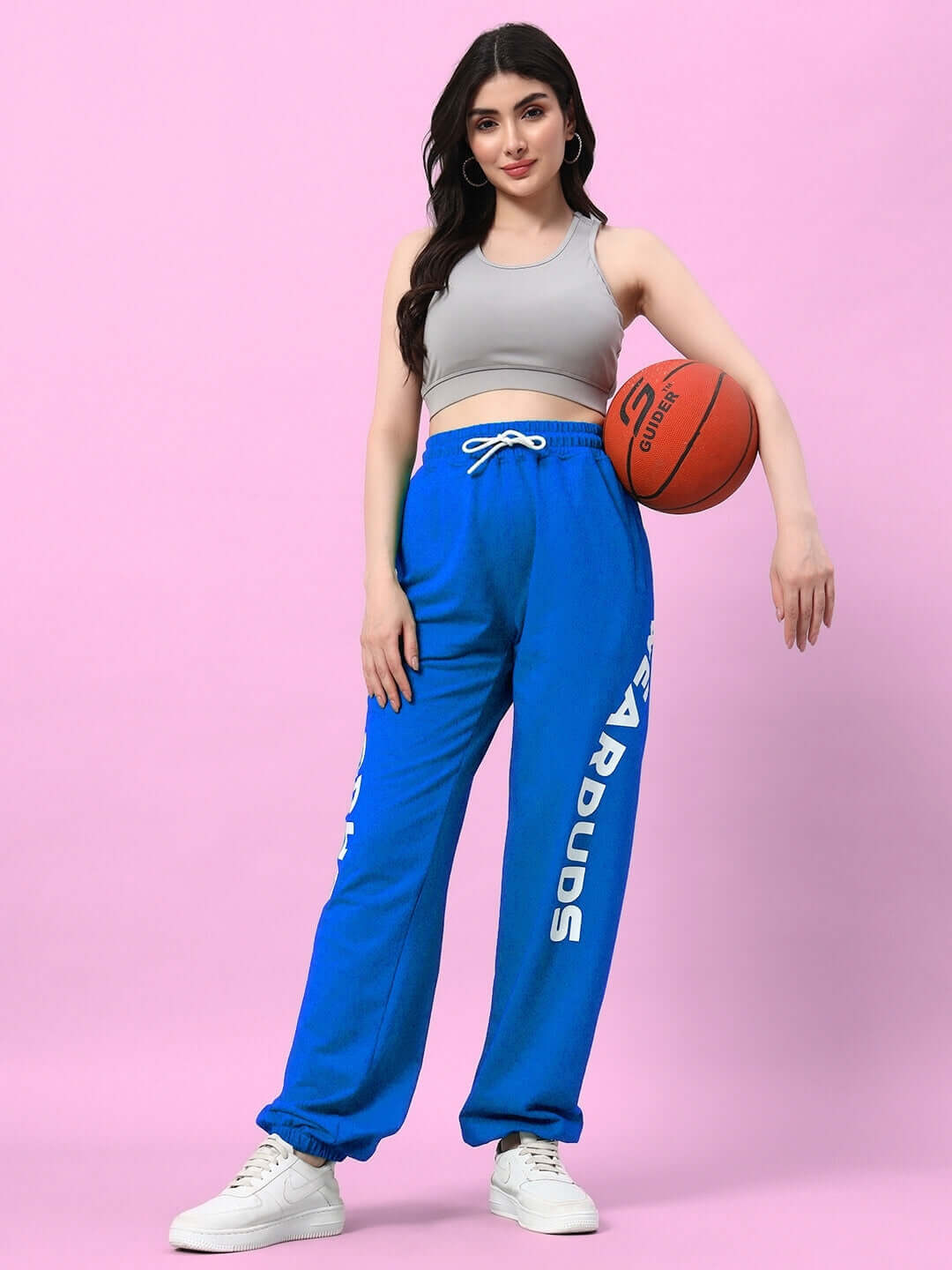 Woman wearing Women's Ellen Relaxed Fit Jogger in blue while holding a basketball against a pink background.