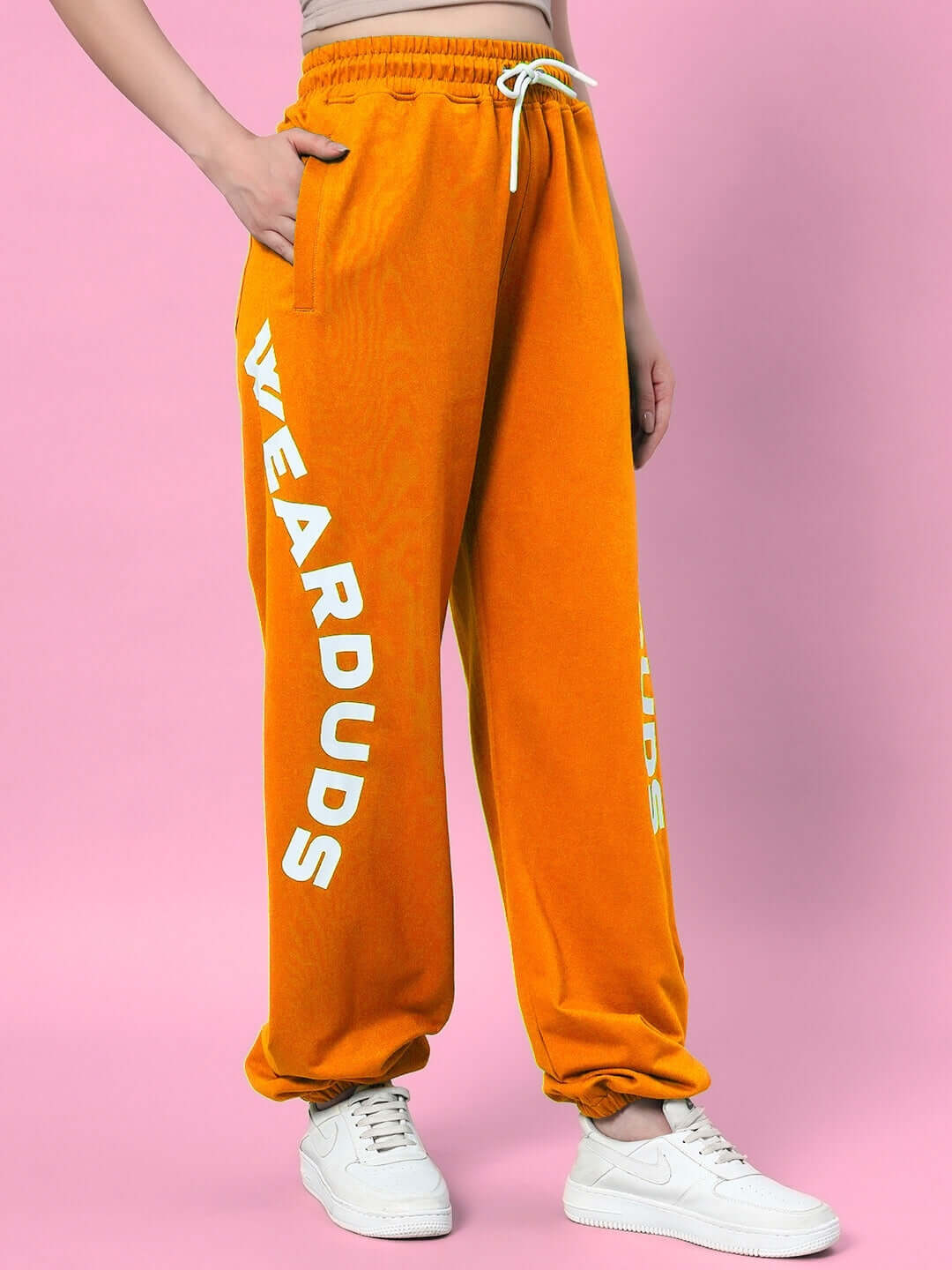 Women's orange relaxed fit jogger pants by DUDS with bold lettering on the side, featuring elastic waistband and white drawstring.