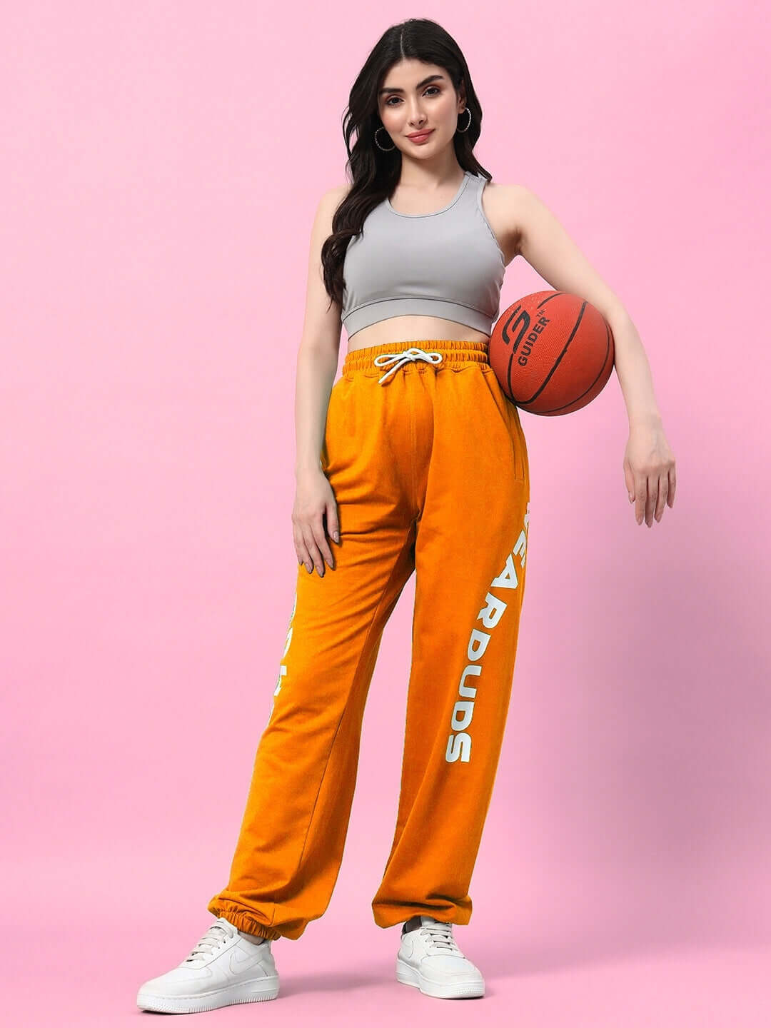 Woman wearing WOMEN'S ELLEN RELAXED FIT JOGGER ORANGE holding basketball