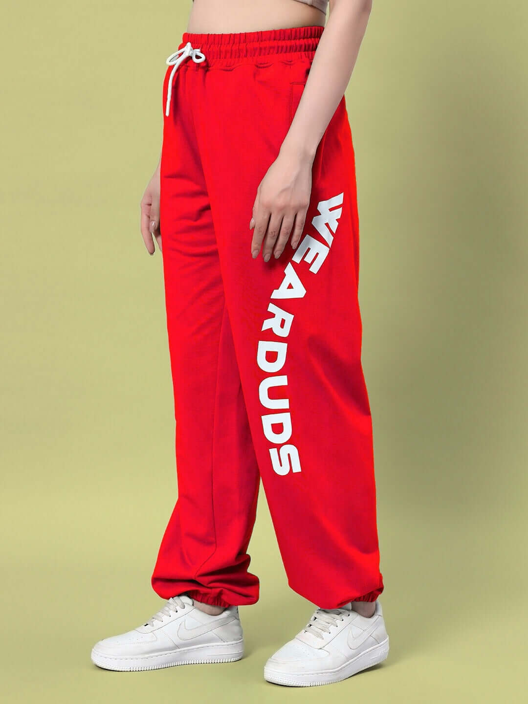 Model wearing WOMEN'S ELLEN RELAXED FIT JOGGER RED, showcasing bold red jogger with comfortable relaxed fit, "WEARDUDS" text on leg.