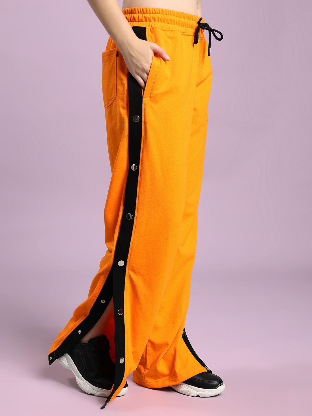 Model wearing WOMEN'S EMBER BOLT SIDE JOGGER ORANGE with side stripe and buttons, vibrant and stylish for casual wear.