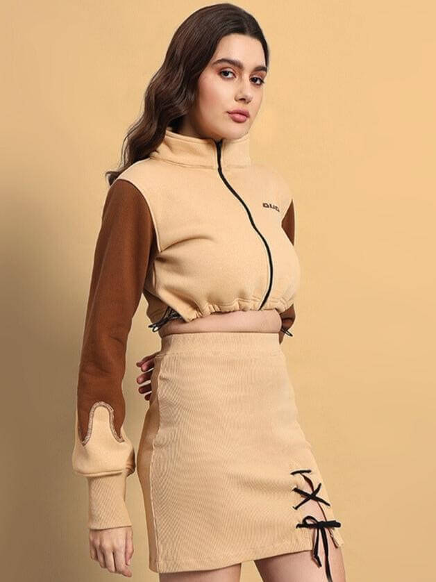 Woman wearing the Women's Emma Shacket in brown-beige with a stylish mini skirt and lace-up details, set against a beige background.