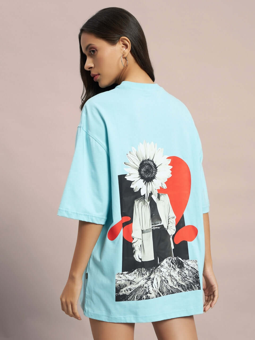Woman wearing sky blue women's oversized t-shirt with artistic back design featuring a sunflower and abstract shapes.