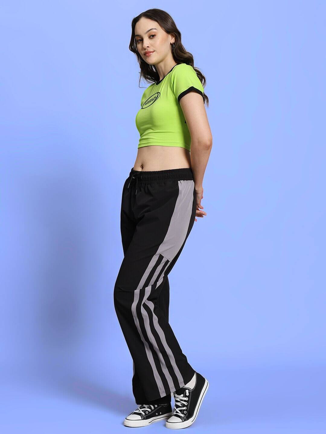 Woman wearing neon green crop top and black joggers with stripes, relaxed fit, elastic waistband, stylish EVA co-ord set.