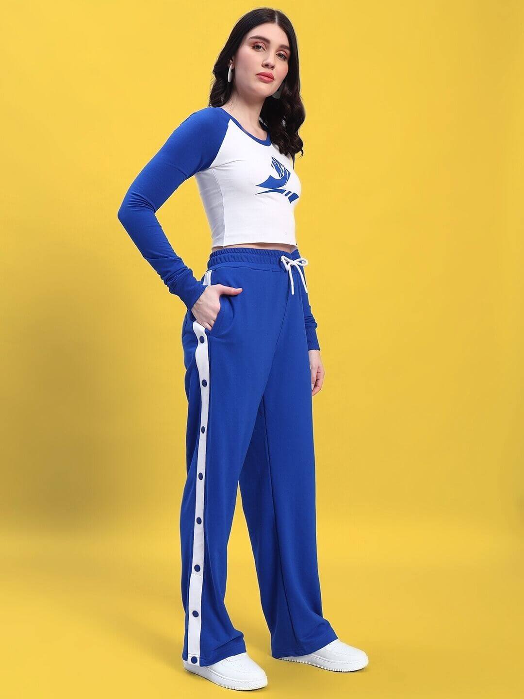 Woman wearing WOMEN'S EZEL CO-ORD SET ROYAL BLUE-WHITE, featuring a royal blue top and white bottoms, standing against a yellow background.
