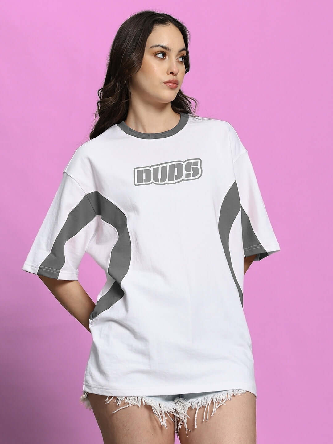 Model wearing women's oversized white grey T-shirt, premium cotton blend, against a pink background.