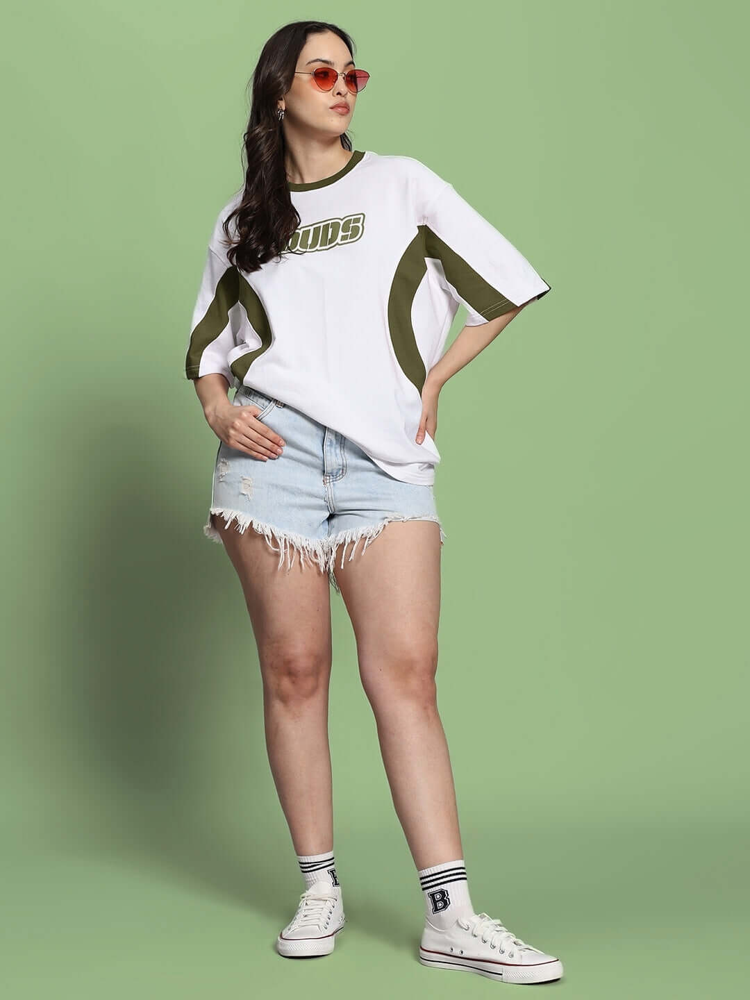 Model wears Women's Ezel oversized T-shirt in white and olive green with denim shorts, showcasing casual chic style.