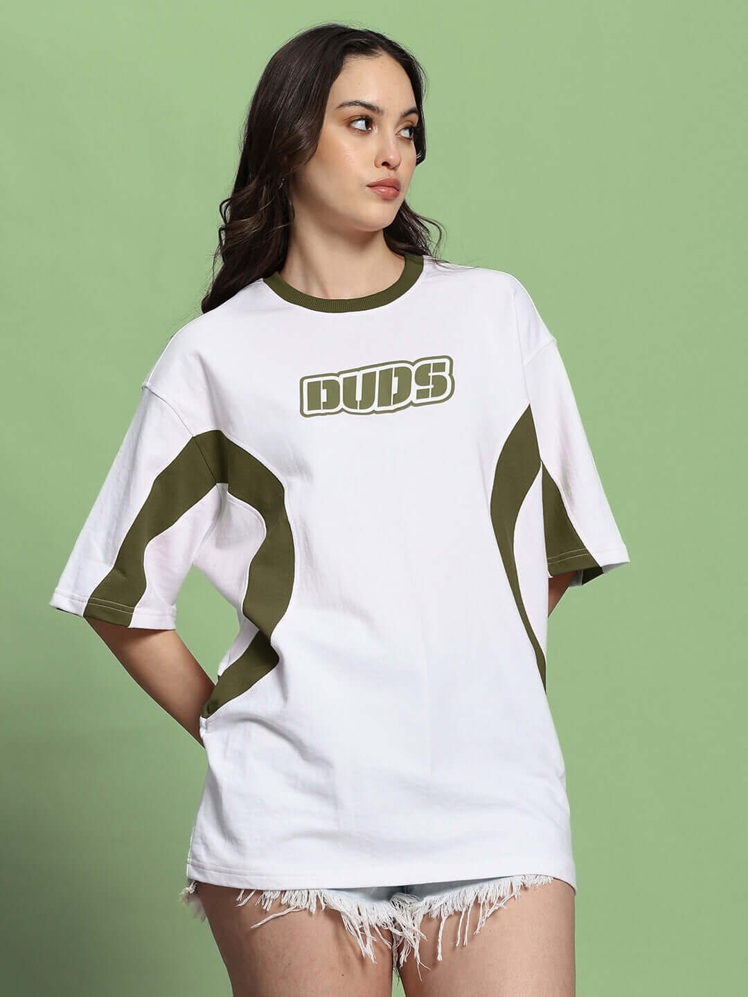 Woman modeling Women's Ezel oversized t-shirt in white olive green, made of 97% cotton French terry lycra, on a green background.