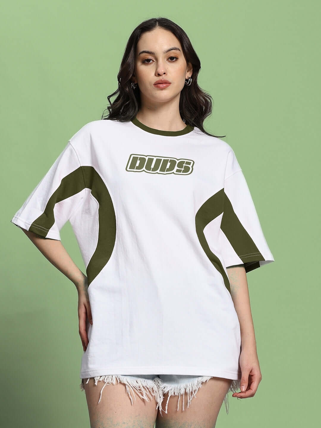 Women's oversized white and olive green t-shirt with a bold logo, featuring premium cotton fabric, styled casually with denim shorts.