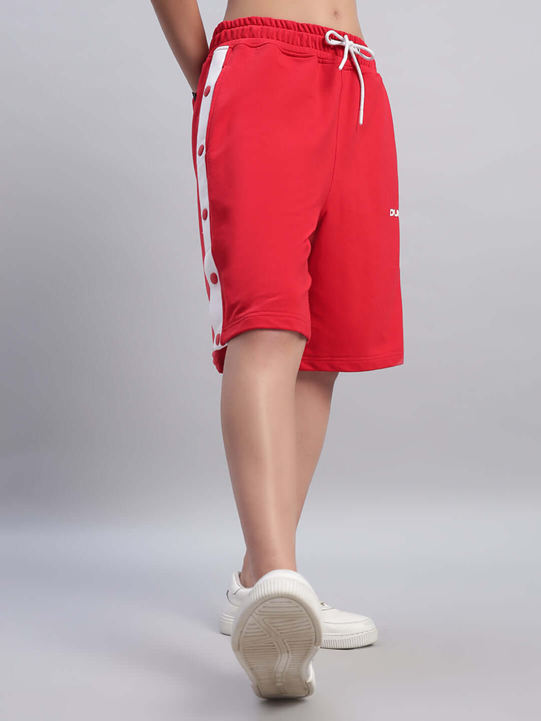 Woman wearing red women's Ezel regular fit shorts with side buttons and white sneakers, showcasing a casual and stylish look.